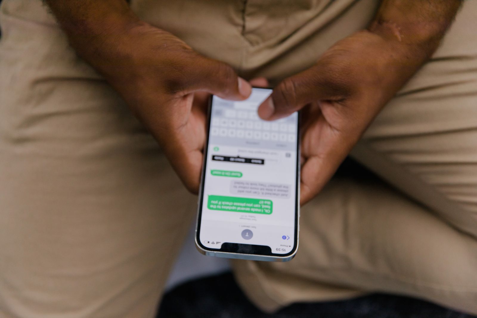 Mãos digitando em um celular com o foco na tela de mensagens